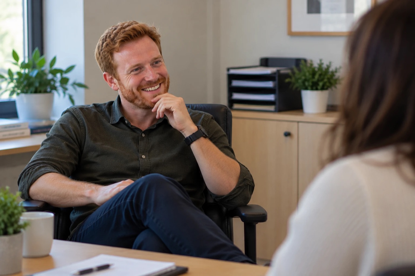 A smiling man with red hair listening during a relaxed one-to-one conversation