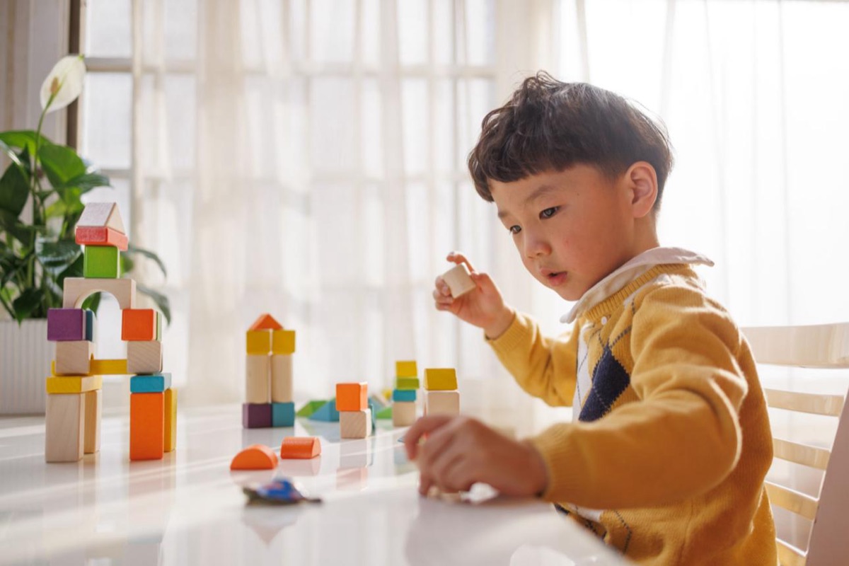 A young child concentrating on building with wooden blocks