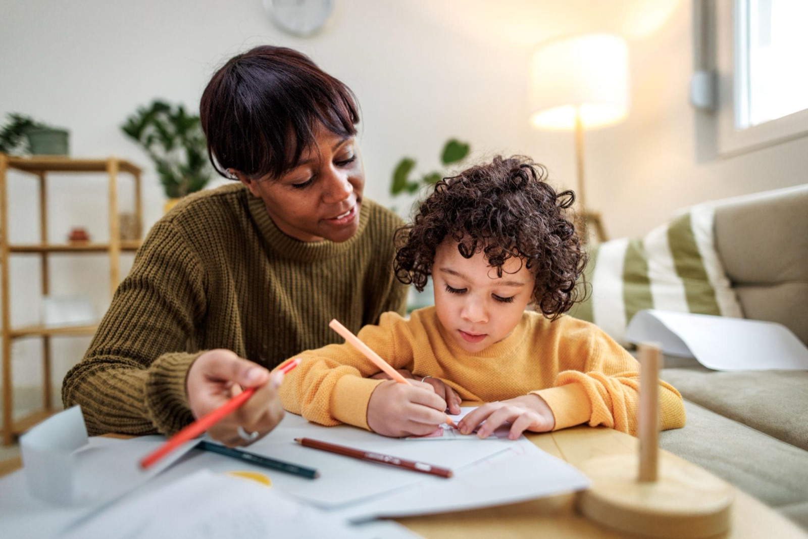 A parent sitting beside their child while the child draws